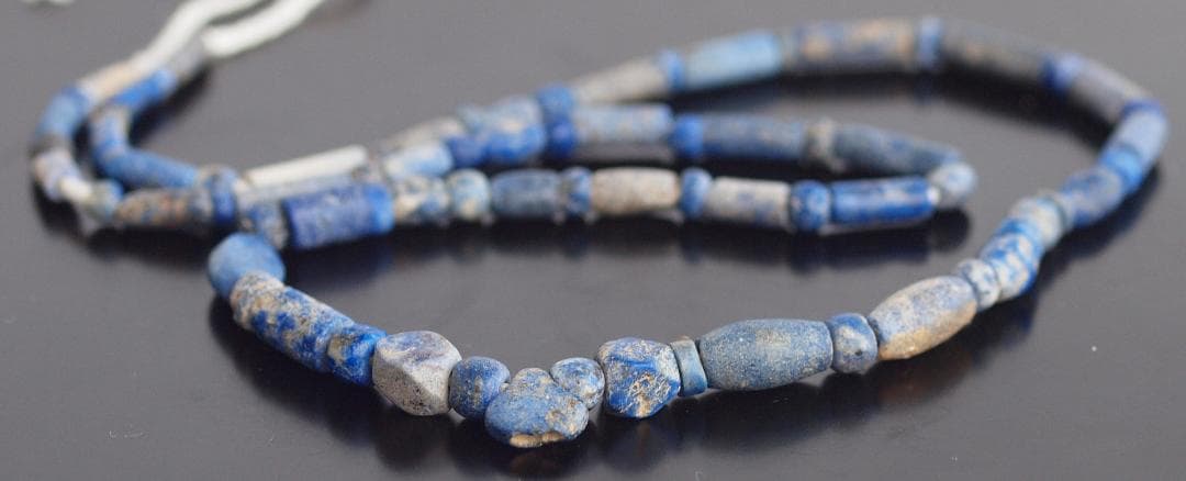 古代濃紺ラピスの管玉や丸玉をほぼ左右対称に編み、トップに斧型や多面体、80個の連